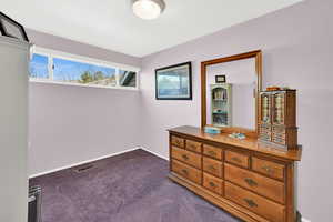 Bedroom with dark colored carpet and baseboards