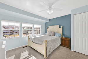 Bedroom with ceiling fan, light colored carpet, and a closet