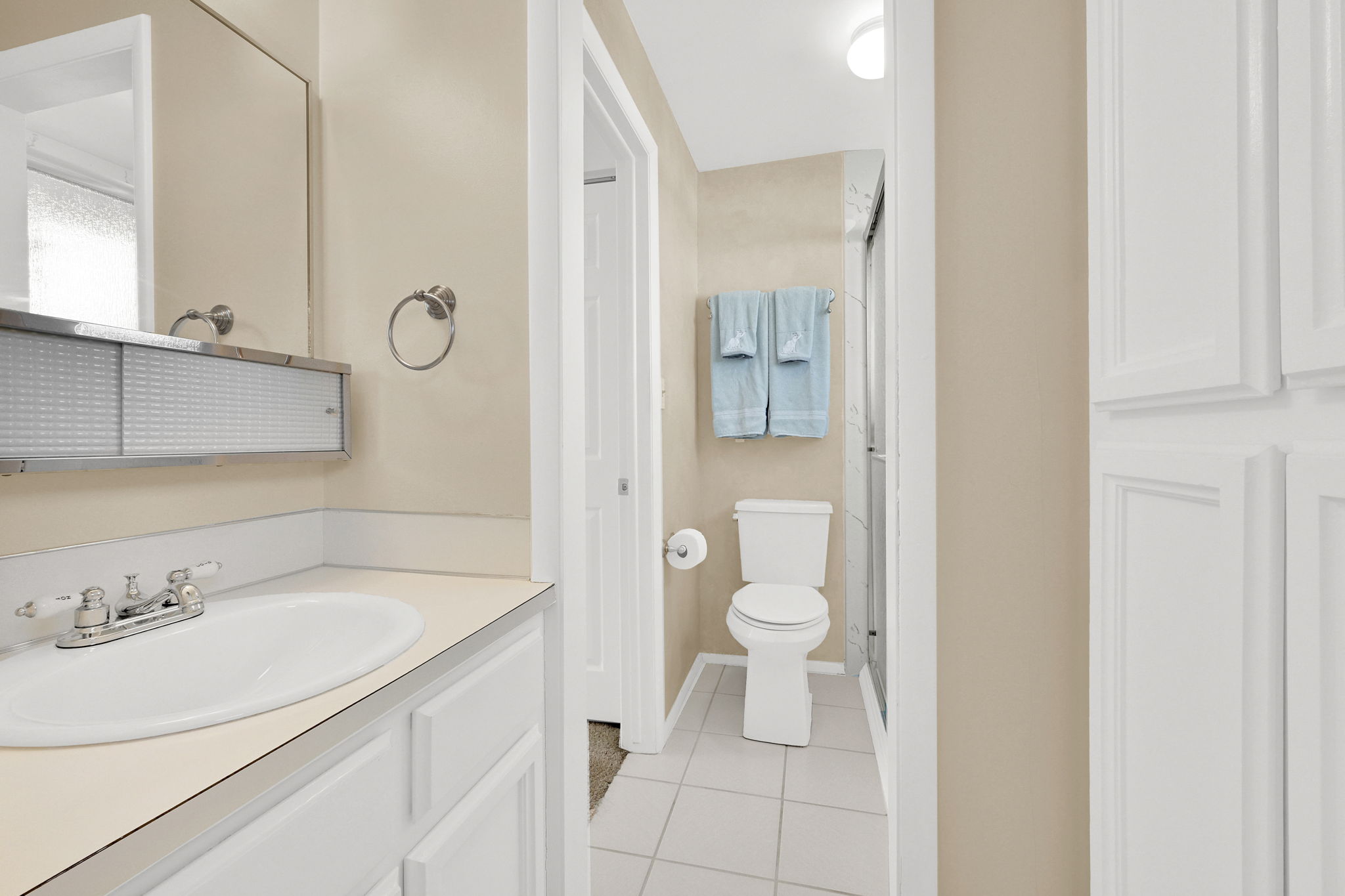 Full bath with vanity, light tile patterned floors, a stall shower, and a closet