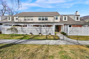 View of front facade featuring a fenced front yard, a chimney, brick siding, and roof with shingles