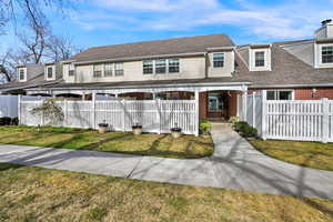 View of front facade featuring a fenced front yard, brick siding, and roof with shingles