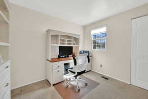 Home office with light colored carpet and baseboards