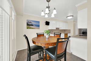 Dining area featuring light colored carpet, suspended lighting, and ornamental molding