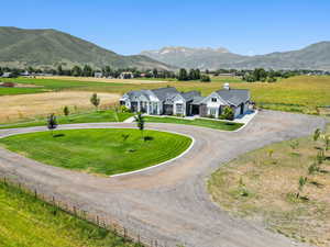 View of front of property with curved driveway, a mountain view, a view of rural / pastoral area, and a garage
