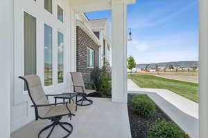 Covered porch featuring a lawn, a mountain view, and a residential view