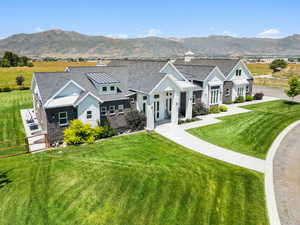 Modern inspired farmhouse featuring a standing seam roof, roof with shingles, a front yard, and a mountain view