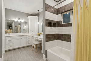 Bathroom featuring vanity, shower / bathtub combination with curtain, and light wood finished floors