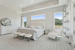 Primary Bedroom with light colored carpet, multiple windows, a raised ceiling, recessed lighting, and a mountain view