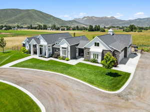 View of front of home featuring dirt driveway, a shingled roof, an attached garage, and a mountain view
