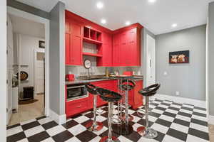Kitchen with dark floors, open shelves, stainless steel microwave, recessed lighting, and dark stone countertops