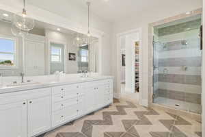 Primary Full bathroom with double vanity, a spacious closet, a shower stall, and recessed lighting