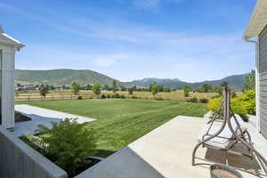 Fenced backyard with a rural view, a patio, and a mountain view