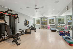 Exercise room with light wood-style flooring, ceiling fan, and recessed lighting