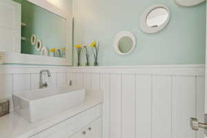 Half Bathroom with a wainscoted wall, vanity, and a decorative wall
