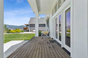 Wooden terrace with a mountain view, french doors, a lawn, and a patio area