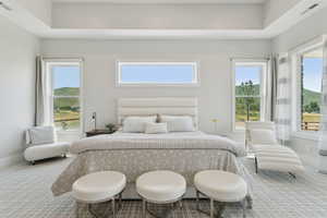 Primary carpeted bedroom featuring multiple windows and a mountain view
