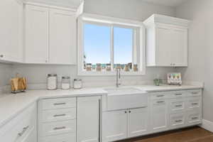 Kitchen with white cabinetry, light stone countertops, and dark wood finished floors