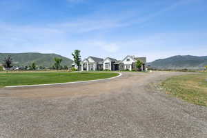 View of front of property featuring a mountain view, curved driveway, and a front lawn