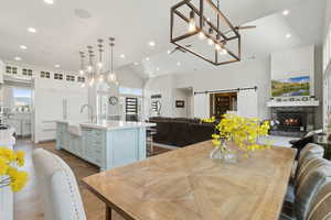 Dining area featuring a barn door, a fireplace, vaulted ceiling, dark wood-style floors, and plenty of natural light