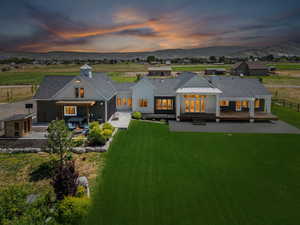 Back of property at dusk with roof with shingles, a mountain view, and board and batten siding