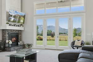 Living area with a high ceiling, light carpet, a brick fireplace, plenty of natural light, and a mountain view