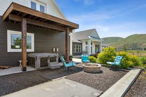 View of patio / terrace with an outdoor fire pit, a mountain view, and a hot tub
