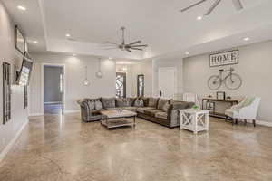 Living area featuring a ceiling fan, a tray ceiling, recessed lighting, and plenty of natural light