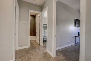 Hall featuring baseboards and concrete flooring