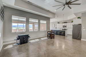 Living area with concrete flooring, ceiling fan, and plenty of natural light