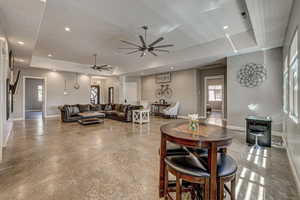 Dining area featuring a raised ceiling, healthy amount of natural light, ceiling fan, recessed lighting, and concrete floors