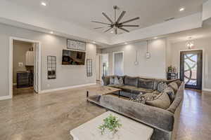 Living room with a ceiling fan, recessed lighting, and finished concrete floors