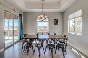 Dining space with hanging lights, concrete flooring, a raised ceiling, and a mountain view