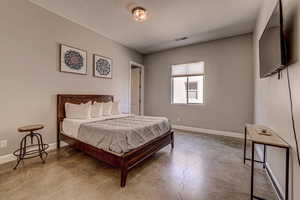 Bedroom with concrete floors and baseboards