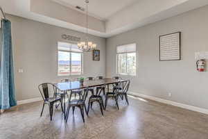 Dining area featuring concrete floors, a raised ceiling, and suspended lighting
