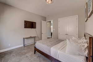 Bedroom with concrete flooring and a closet