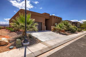 Pueblo revival-style home featuring a garage, stucco siding, and driveway
