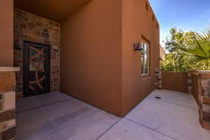 Doorway to property featuring stone siding, a patio, and stucco siding