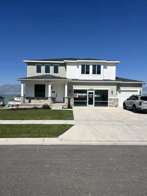 View of front of house featuring covered porch, stone siding, concrete driveway, a mountain view, and a garage