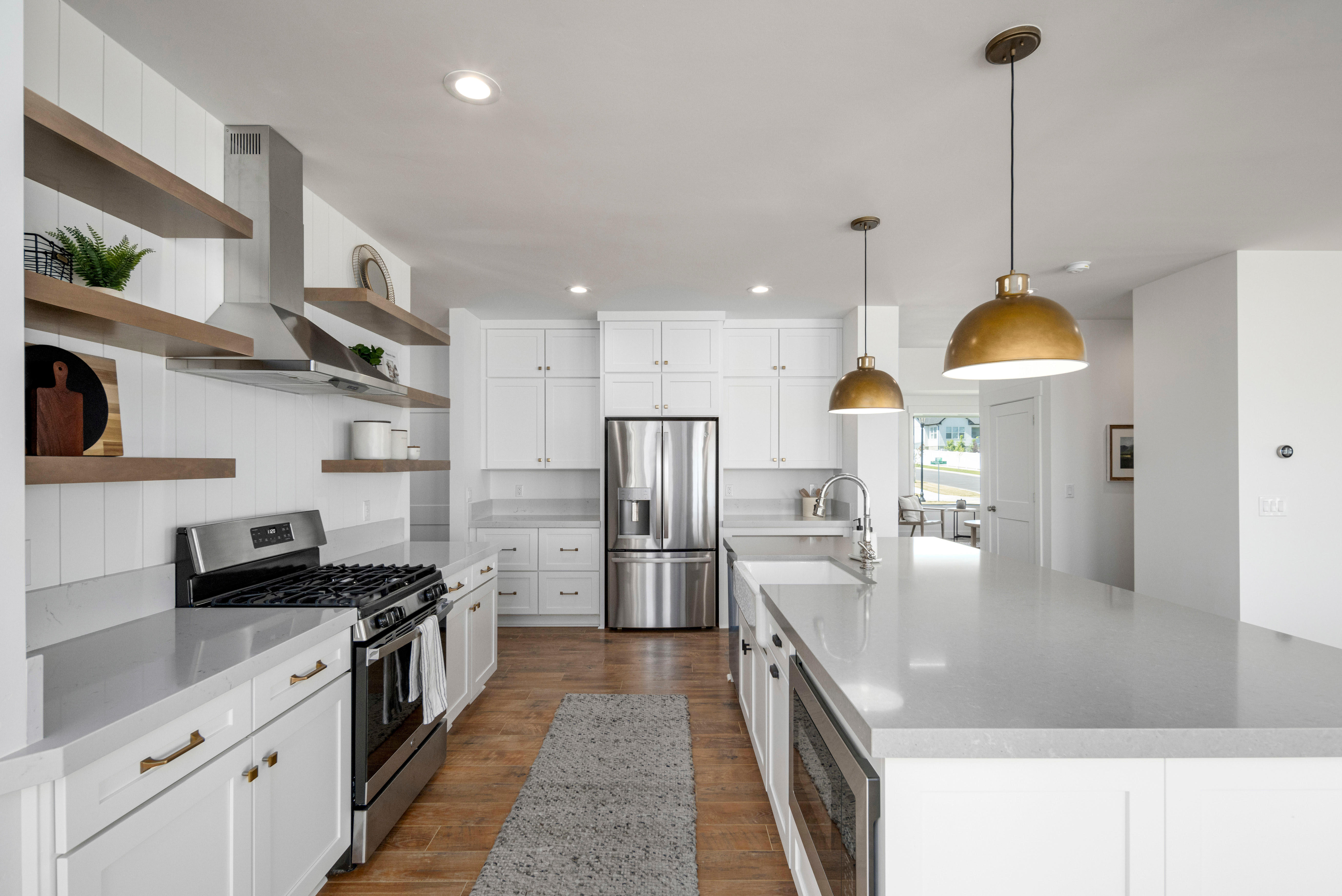 Kitchen featuring stainless steel appliances, open shelves, white cabinetry, dark wood-type flooring, and a spacious island