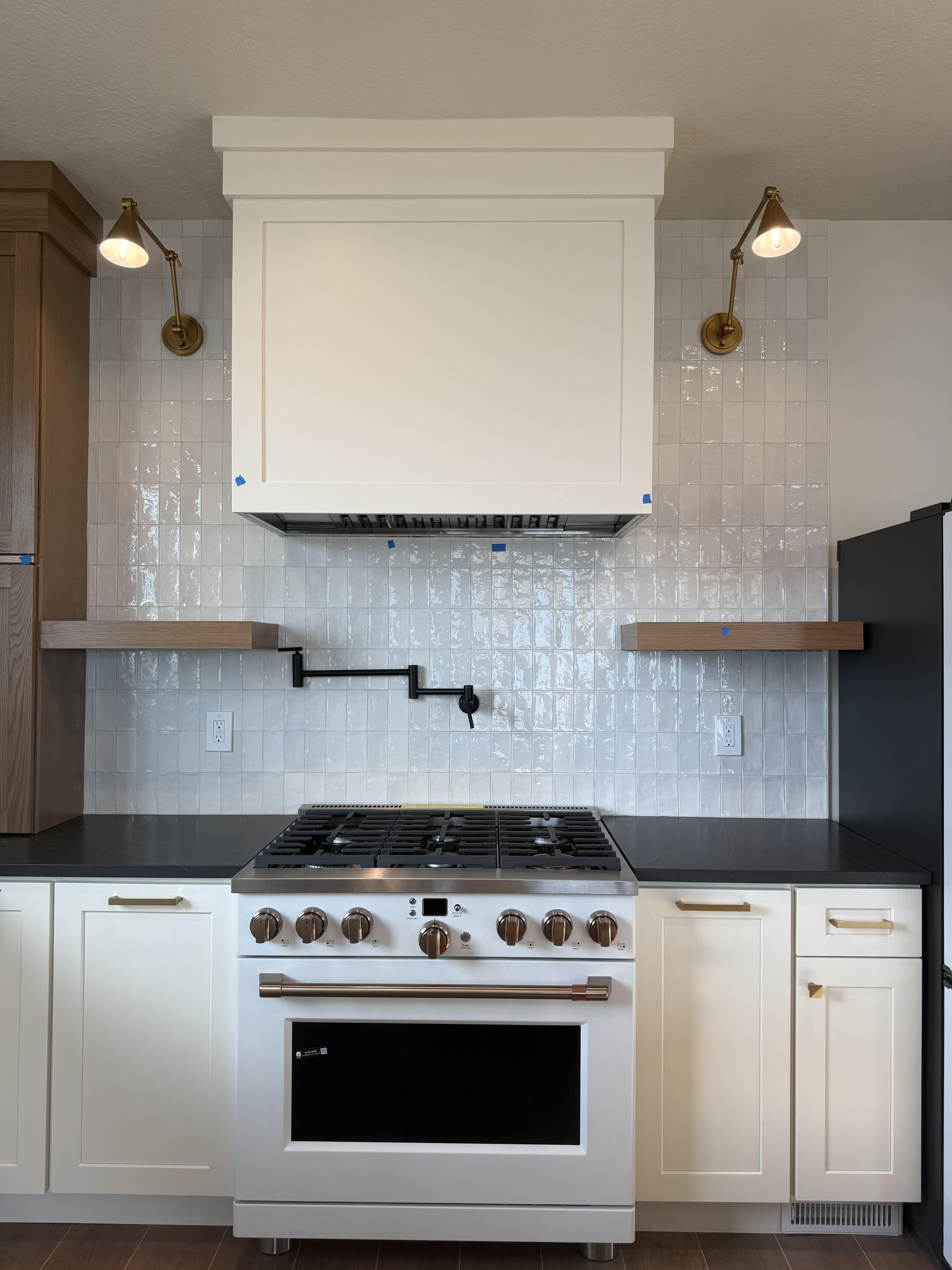 Kitchen with high end range, white cabinets, decorative backsplash, and open shelves