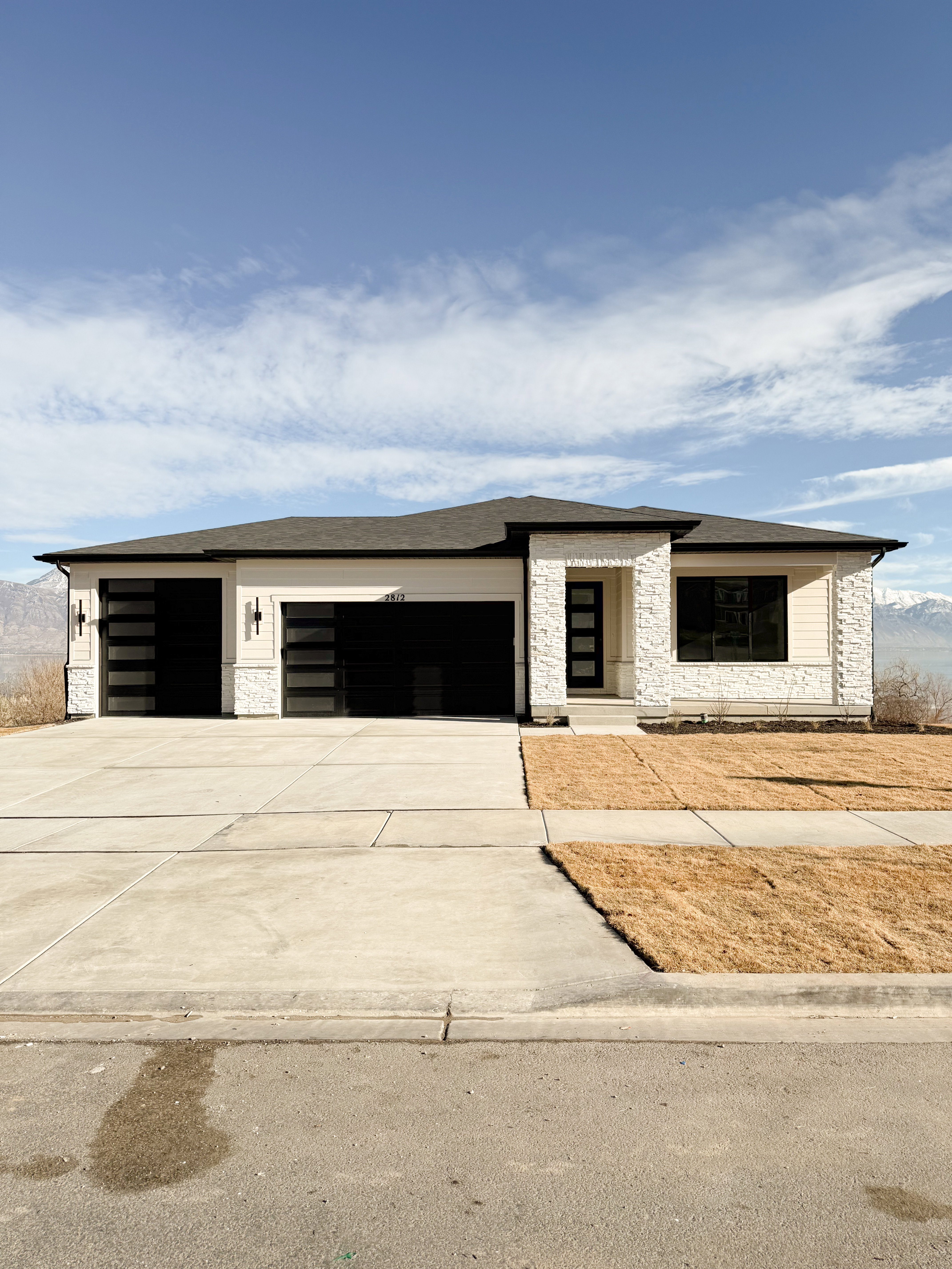 View of front of home with stone siding, concrete driveway, an attached garage, and roof with shingles