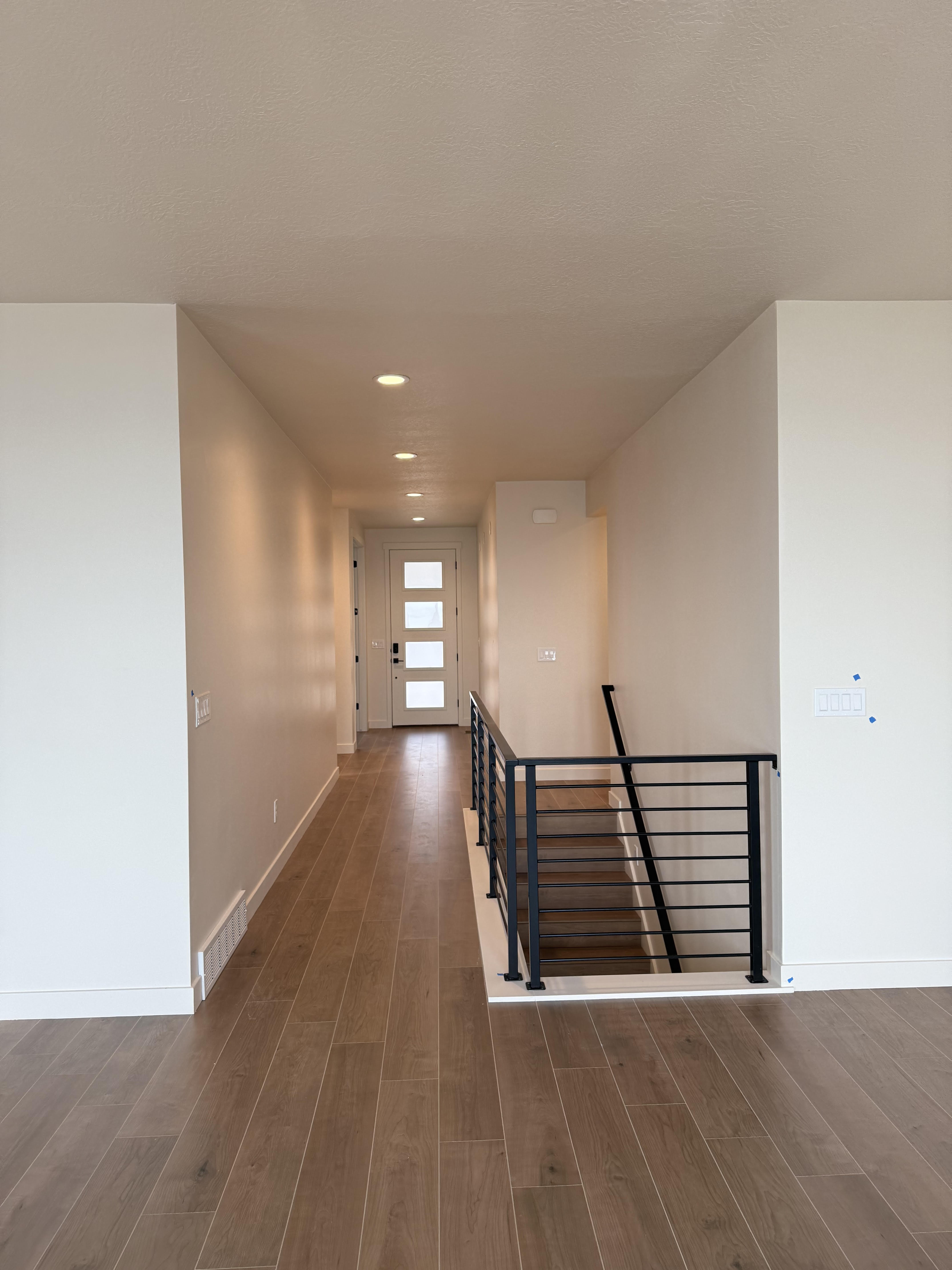 Hallway with dark wood-type flooring, an upstairs landing, and recessed lighting