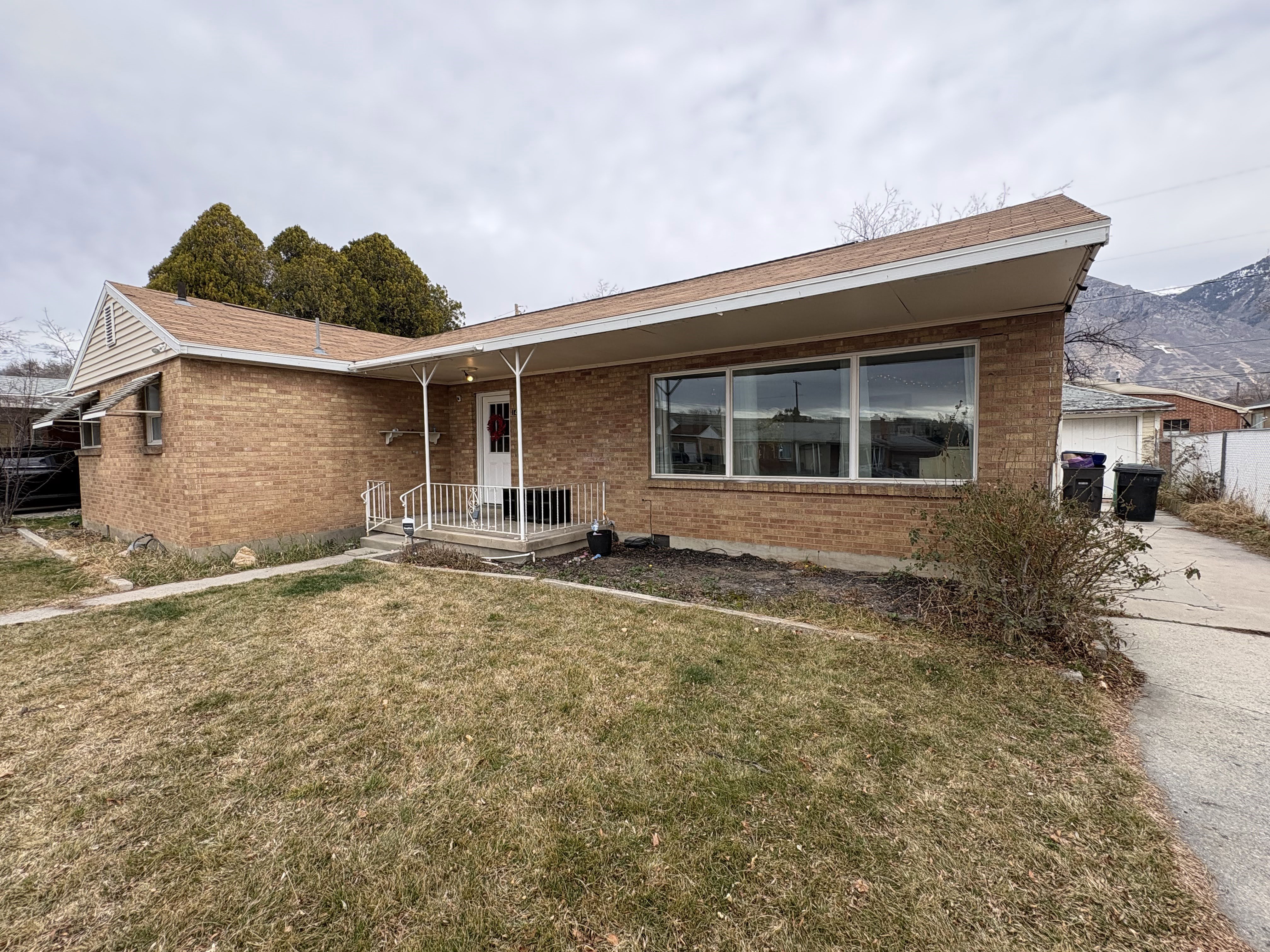 View of front facade with brick siding, a front lawn, and covered porch