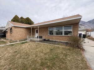 View of front facade with brick siding, a front lawn, and covered porch