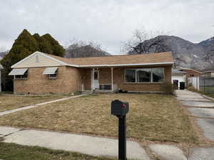 Ranch-style house featuring a front yard, a porch, brick siding, and a mountain view