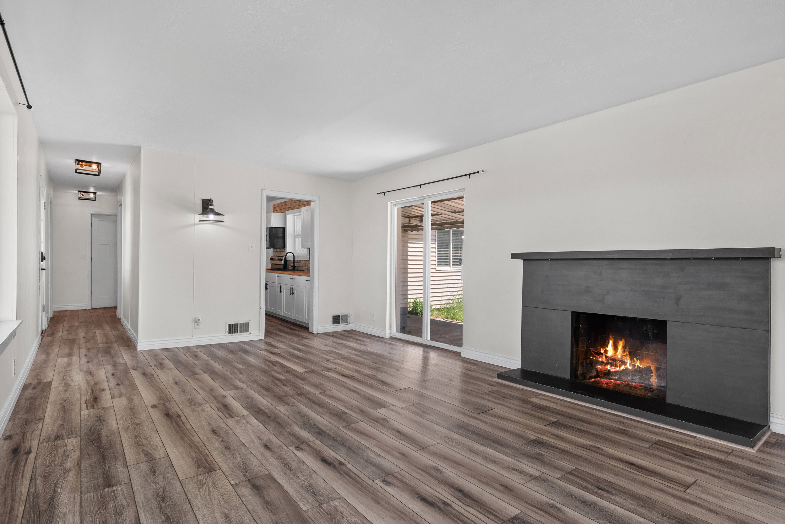 Living space featuring wood-finish flooring, a contemporary dark-toned fireplace, and a sliding glass door