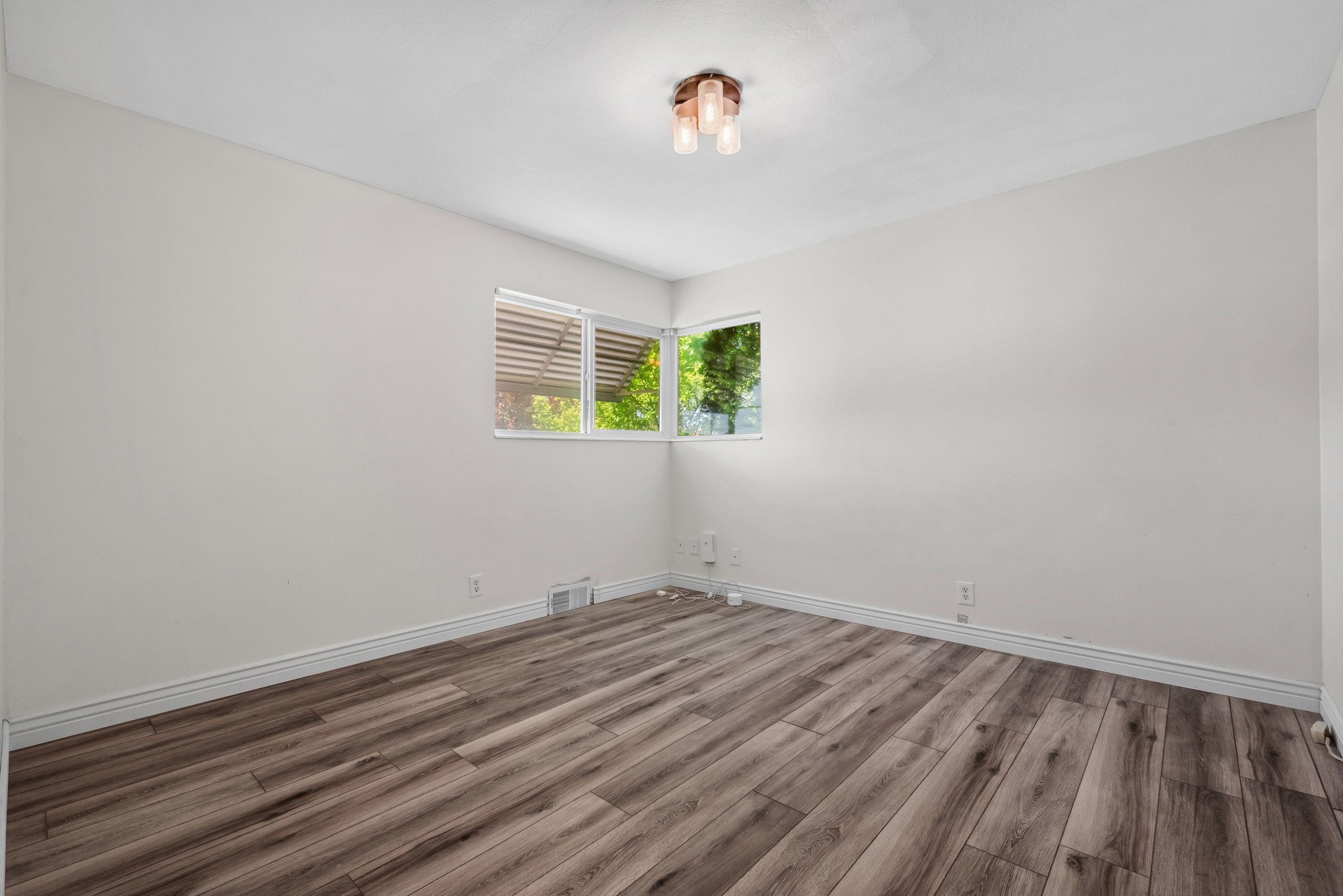 Room featuring wood-finish flooring, white baseboards, and light-toned walls