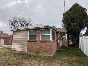 View of side of home featuring brick siding and a metal roof