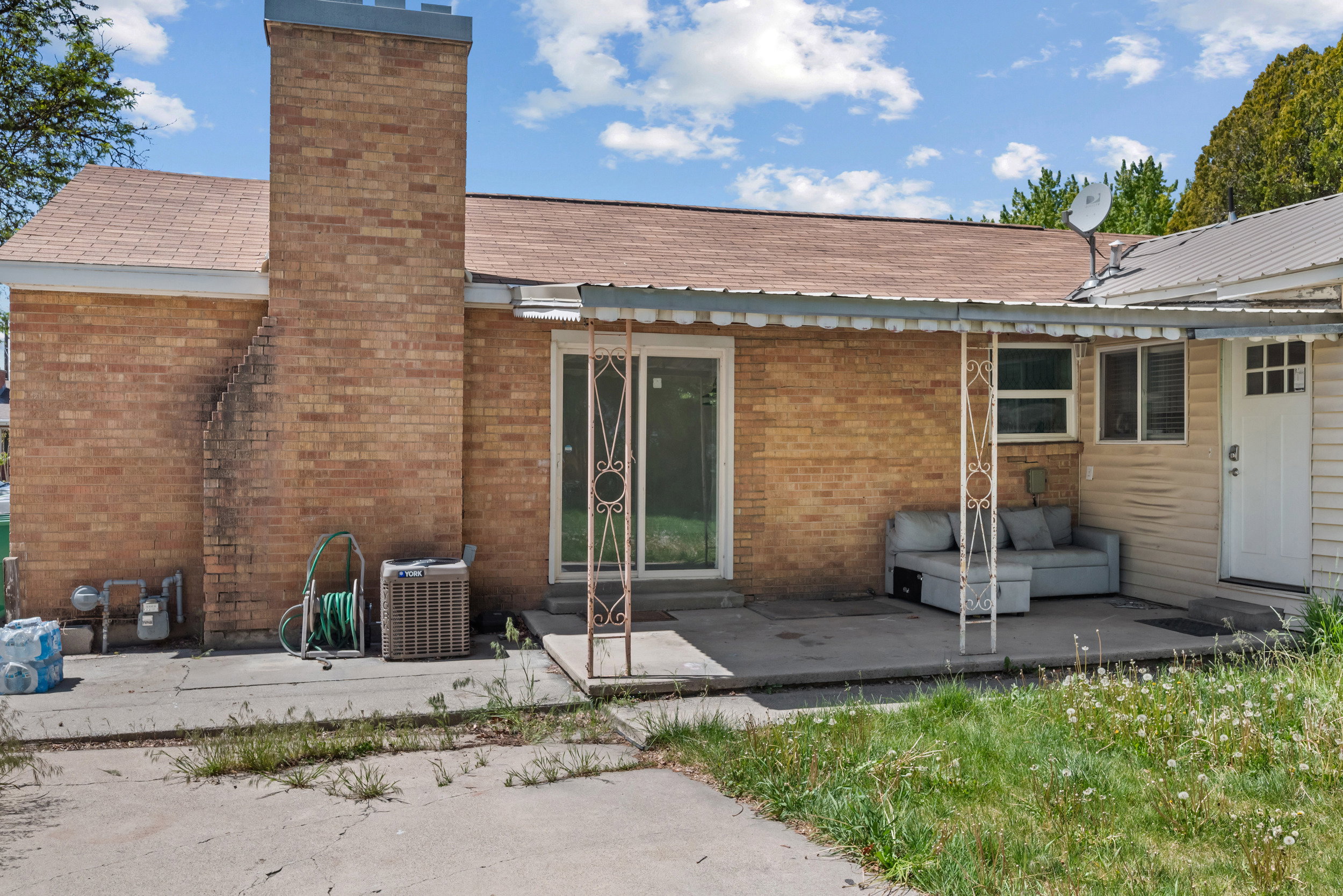 Rear exterior featuring brick siding, a prominent brick chimney, and a brown shingle roof