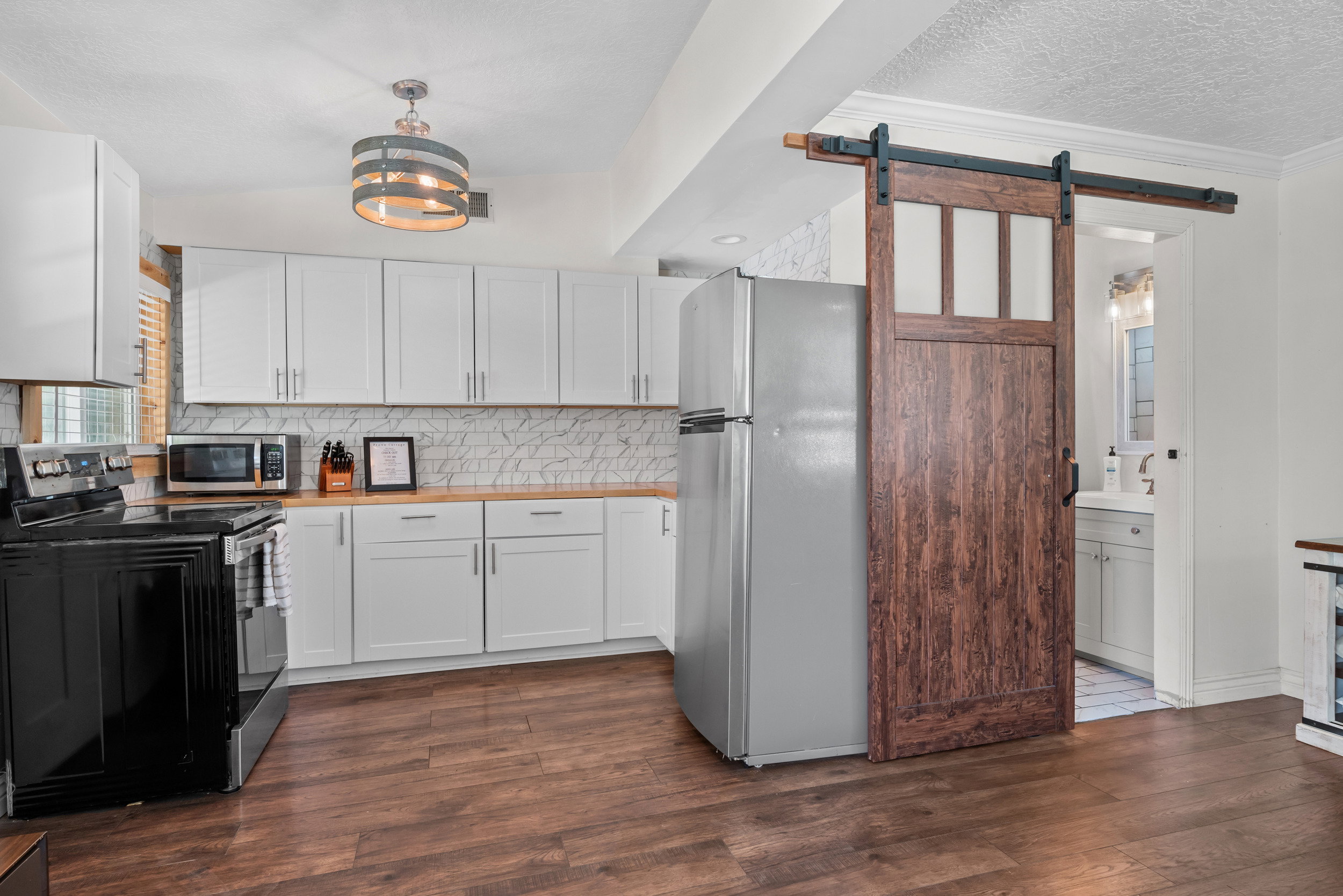 Kitchen featuring white shaker cabinetry, butcher block countertops, and a white marble-look tile backsplash
